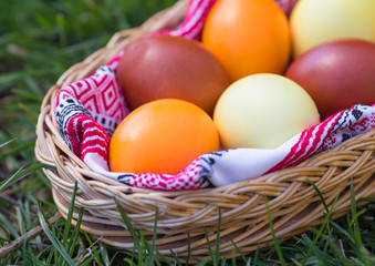 Unique hand painted Easter eggs in basket on grass. Traditional decoration in sun light