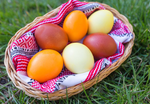 Unique hand painted Easter eggs in basket on grass. Traditional decoration in sun light