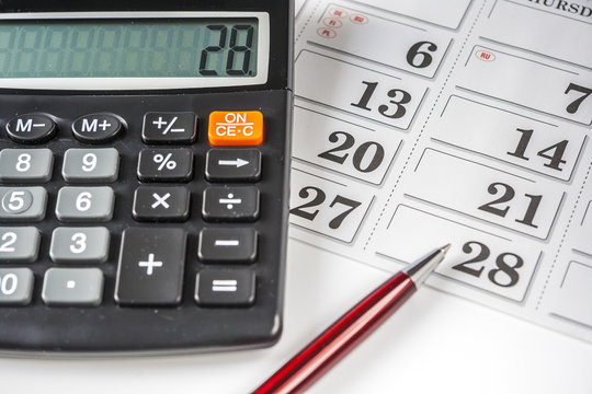 Calculator And Pen Resting On An Calendar