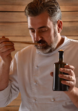 Cocinero sujetando y probando una botella de aceite de oliva.