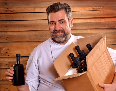 Cocinero sujetando una caja con botellas de aceite de oliva,aceituna.