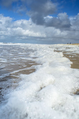 Wind and waves create foam on the beach