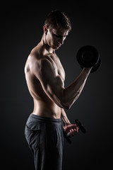 Fototapeta na wymiar Muscular man working out doing exercises with dumbbells at biceps