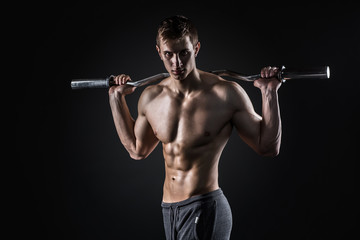 Strong man holding barbell on his shoulders, looking at camera