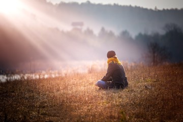 Young woman sitting on grass on meadow