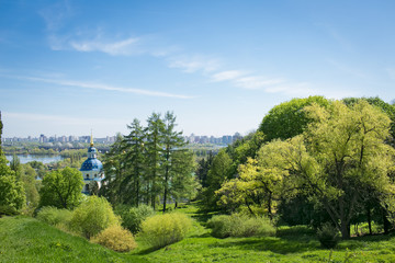 landscape with green grass, blue sky, church, city