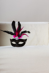 Black carnival mask laying on sofa