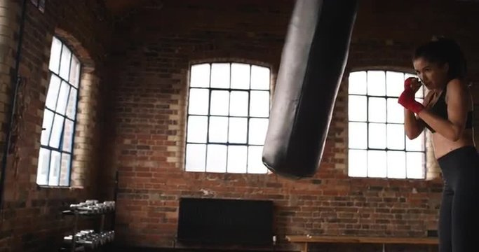 Kickboxing woman training punching bag in fitness studio