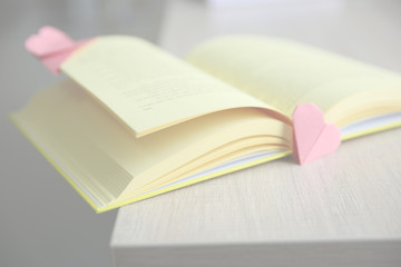 Book and origami heart as bookmarks on wooden table