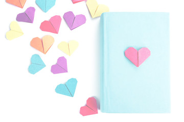 Book and origami hearts on light background