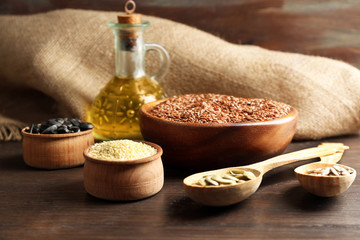 Flax, sesame, pumpkin and sunflower seeds with oil on wooden table background, closeup