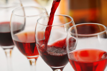 Red wine pouring into glasses, closeup