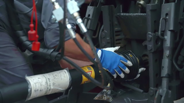 Worker in a factory is trying to connect a trailer and a tractor