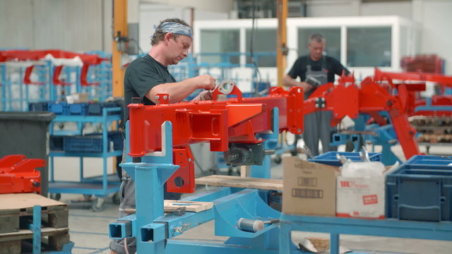 A worker is taking one device apart and putting it somewhere else