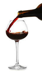 Red wine pouring in glass, isolated on white