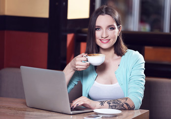 Young woman working with laptop in cafe