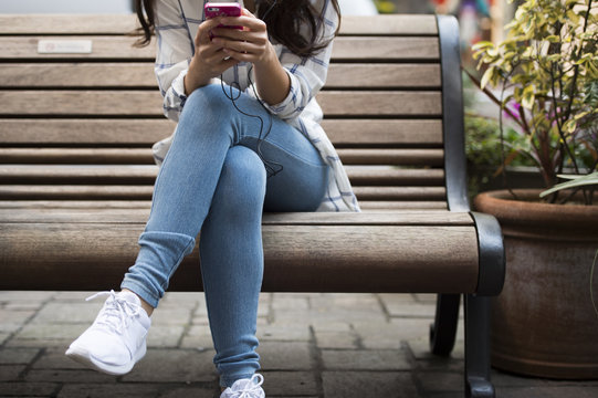 Young women are using a smart phone sitting on a bench