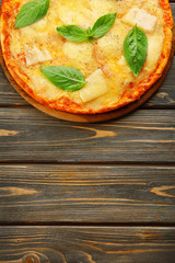 Tasty pizza decorated with basil  on wooden background, close up