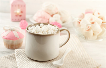 Mug of hot chocolate with marshmallows, on light wooden background