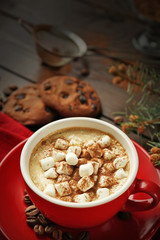 Mug of hot chocolate with marshmallows, fir tree branch on wooden background