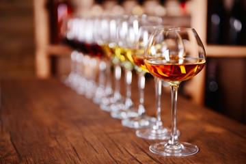 Many glasses of different wine in a row on bar counter