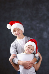 Brothers in Santa hats on grey background
