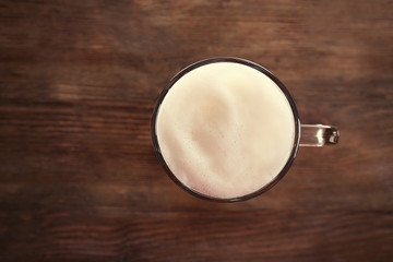 Top view of glass with light beer on wooden background
