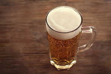 Glass of light beer on wooden background