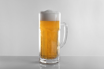 Glass of lager beer on light grey background