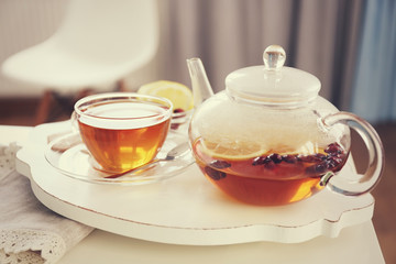Tea set with hot tea and breakfast on a white wooden mat on the table