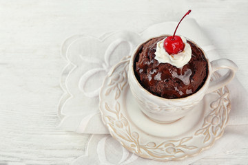 Chocolate mug cake with cream and cherry on a white napkin