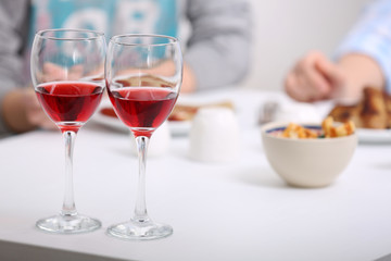 Dinner with glasses of wine on light blurred background