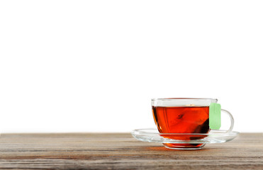 Cup of tea with tea bag on wooden background against grey background