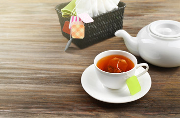 Cup of tea with tea bags and teapot on wooden table background