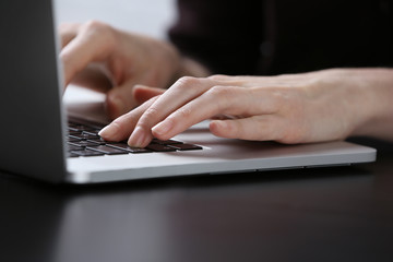 Obraz na płótnie Canvas Female hands using laptop on dark wooden table, close up
