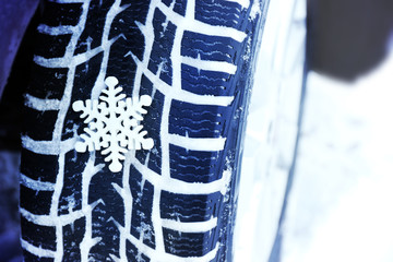 Winter tires in snow with snowflake, closeup