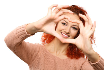 Red-haired young woman making heart with hands, isolated on white