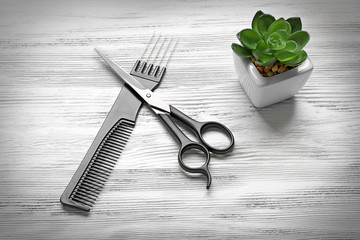 Comb, scissors and flower on wooden background