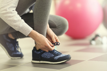 Woman tying shoelaces of sneaker on a floor