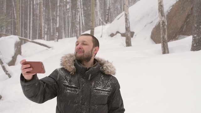 Man taking a selfie in a winter forest under the snow