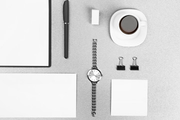 Office set with white sheets of paper, cup of coffee, watch and stationery on grey background