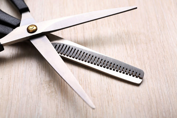 Barber set with two scissors on light wooden table, close up