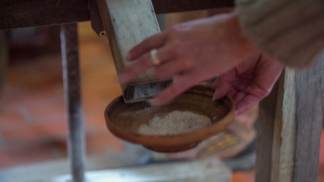 Man is rotating the millstone and the woman collect the fresh flour