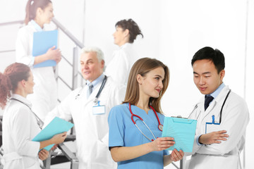 Fototapeta premium Speaking doctors and their colleagues on background indoors