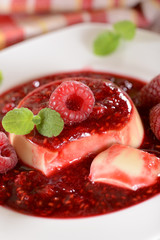 Panna cotta dessert with fresh raspberries and mint leaves on to