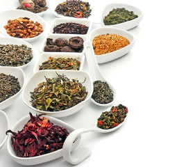 Variety of dry tea in bowls and spoons isolated on white