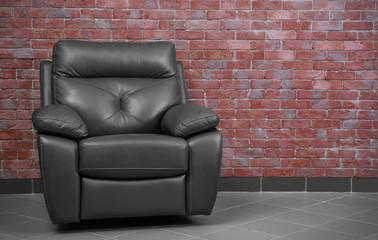 Brown leather armchair against brick wall background