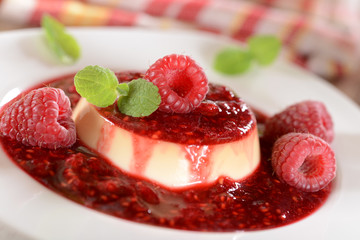 Panna cotta dessert with fresh raspberries and mint leaves on to