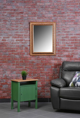 Brown leather armchair and green small table against brick wall background