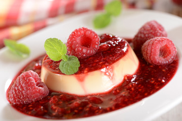 Panna cotta dessert with fresh raspberries and mint leaves on to